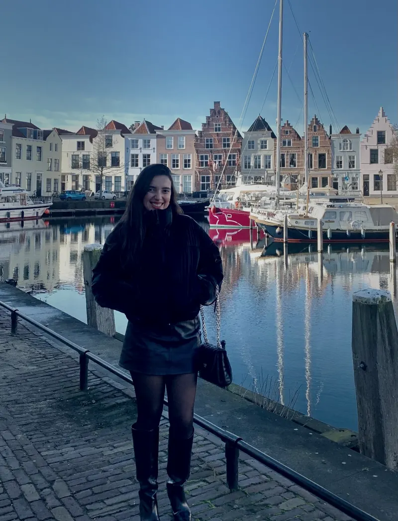 Alicia, of Marketing for you, beside a canal in the Netherlands, with a row of Dutch gabled houses behind her